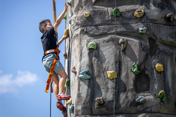 A young boy climbing a wall and having fun at an event.
