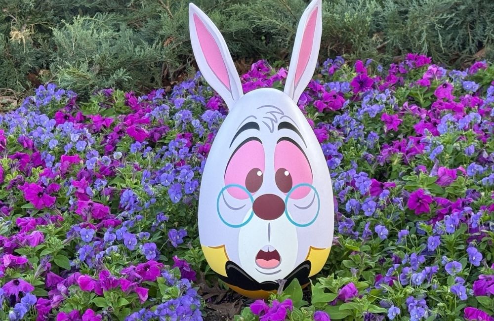 Image: A cardboard cutout of the White Rabbit set among a field of blue and purple flowers
