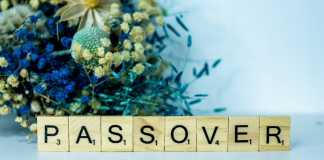 Image: A bouquet of blue dried flowers behind Scrabble tiles spelling out PASSOVER