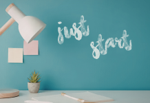 Image: A desk with a wooden desk lamp and the words "Just Start" written on a wall in the background