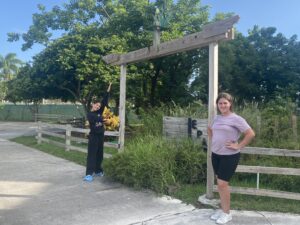 Image: Two people stand on either side of the entrance to a garden