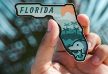 Image: A hand holds a magnet shaped like the state of Florida