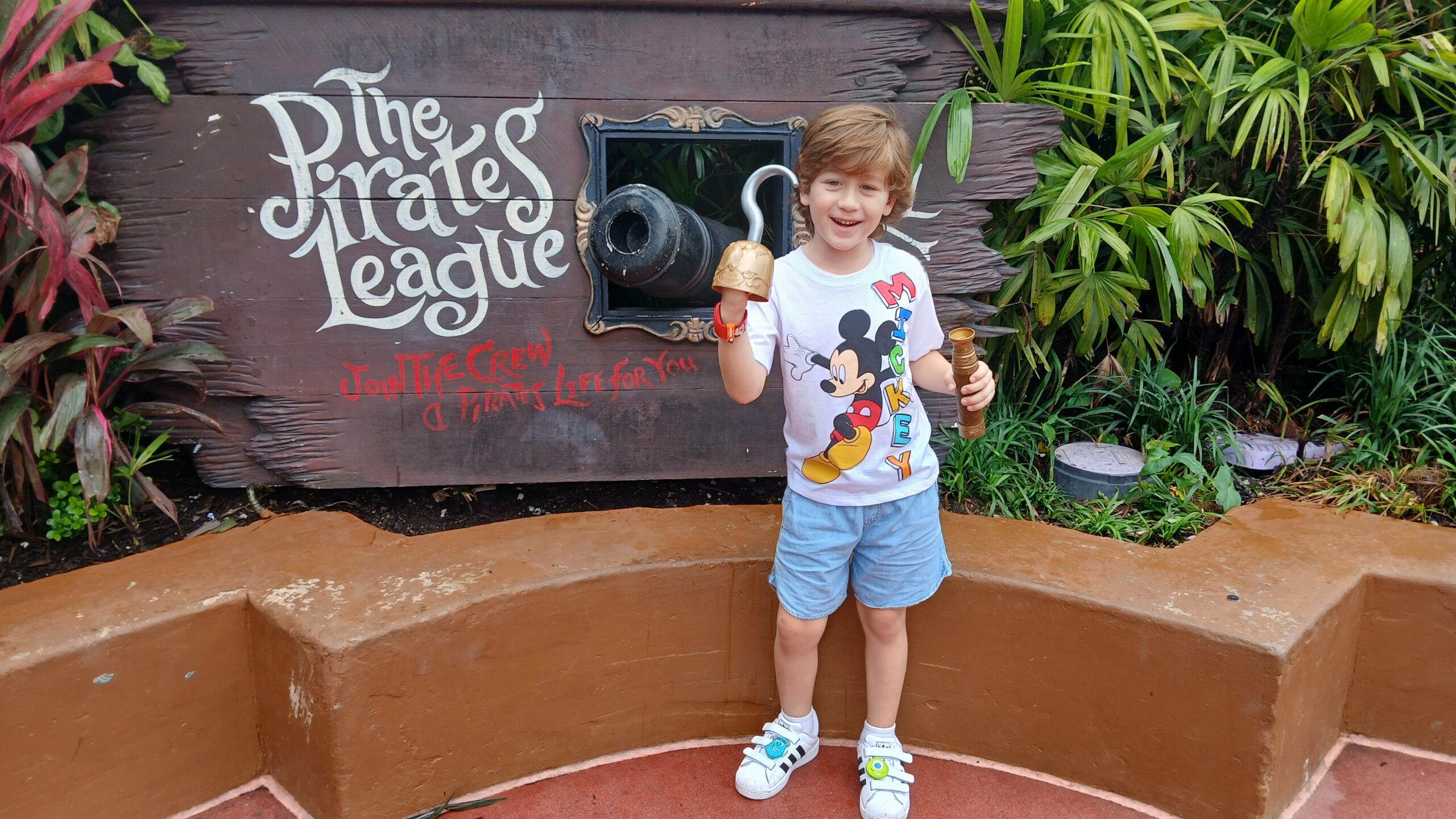 Image: A child poses for a photo in front of The Pirates League in Adventureland at Magic Kingdom