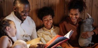 Image: A father and mother enjoy a picture book with their daughter and son