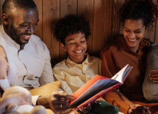 Image: A father and mother enjoy a picture book with their daughter and son