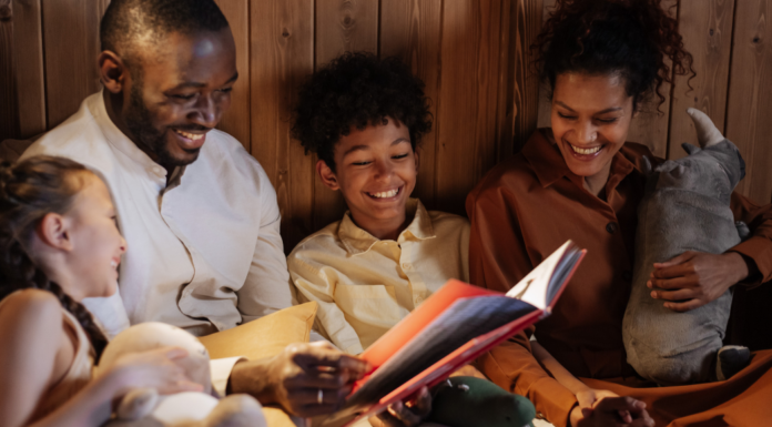 Image: A father and mother enjoy a picture book with their daughter and son