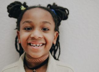 Image: An elementary aged child with pigtails smiles for the camera