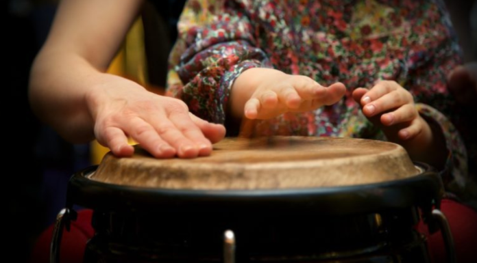 Hispanic Heritage in Miami | More Than Just a Month Image: A parent plays a bongo drum with their young child