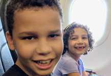 Image: Two kids smiling from their seats on an airplane
