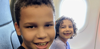 Image: Two kids smiling from their seats on an airplane