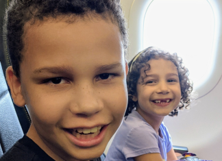 Image: Two kids smiling from their seats on an airplane