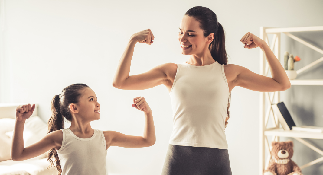 Image: A mother and daughter flex their arm muscles together