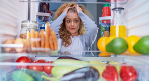 Image: A woman looks into a refrigerator with her hands on her head