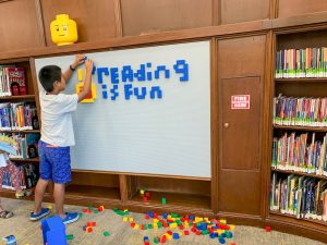 Image: A boy uses Legos to spell out "Reading is Fun"