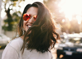 Image: A confident woman wearing sunglasses and smiling as she crosses the street
