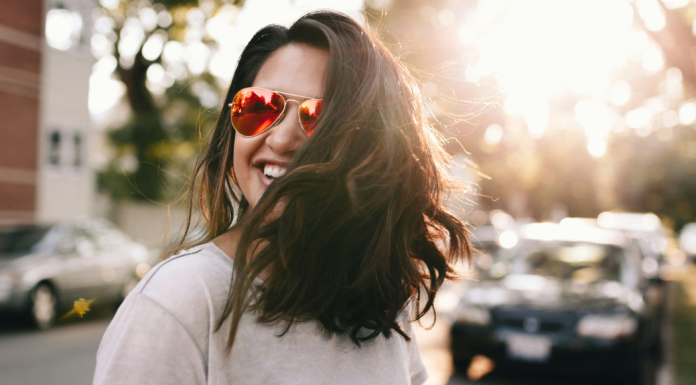 Image: A confident woman wearing sunglasses and smiling as she crosses the street