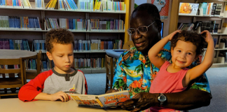 Image: A grandfather reads books to his grandchildren at the library
