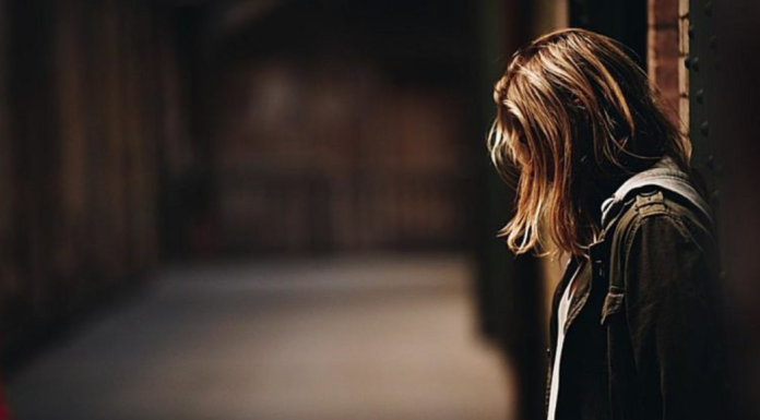 The Redemptive Work of Unmerited Suffering: What I’m Learning Image: A woman stands with her back to a wall, looking down at the ground