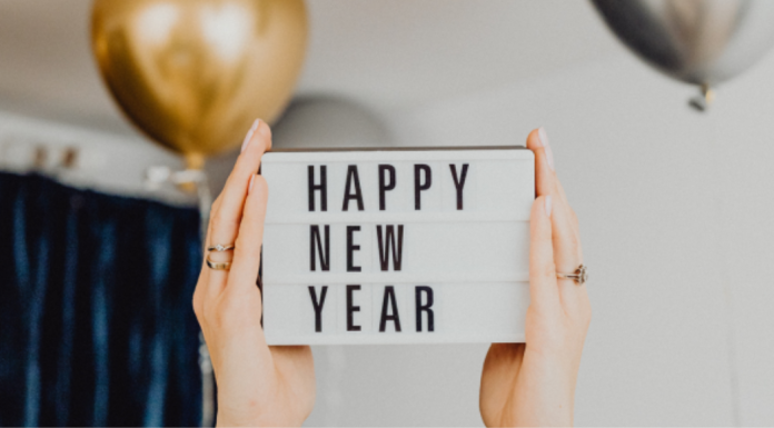 No more “New Year, New Me.” Here’s Why. Image: Hands hold up a letter board that reads "Happy New Year"