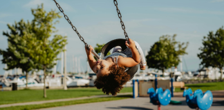 Image: A little girl in a toddler swing at a playground