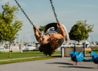 Image: A little girl in a toddler swing at a playground