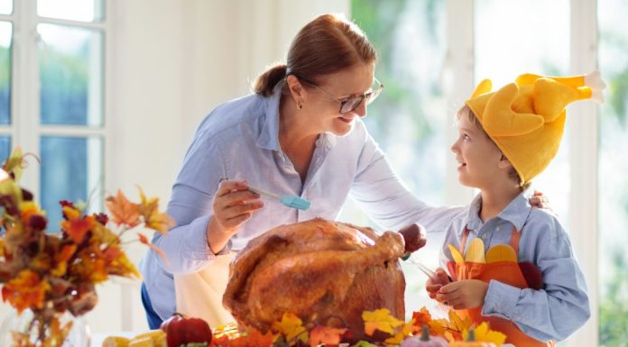 Image: A grandmother bastes a Thanksgiving turkey with a grandchild