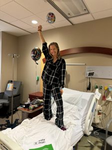 Image: Lindsey stands on her hospital bed with her fist in the air