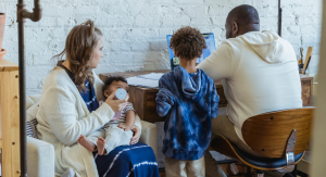 Image: A family sits together and talks about what they see on a computer screen