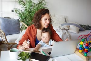 Image: A mother works from home while her toddler sits on her lap