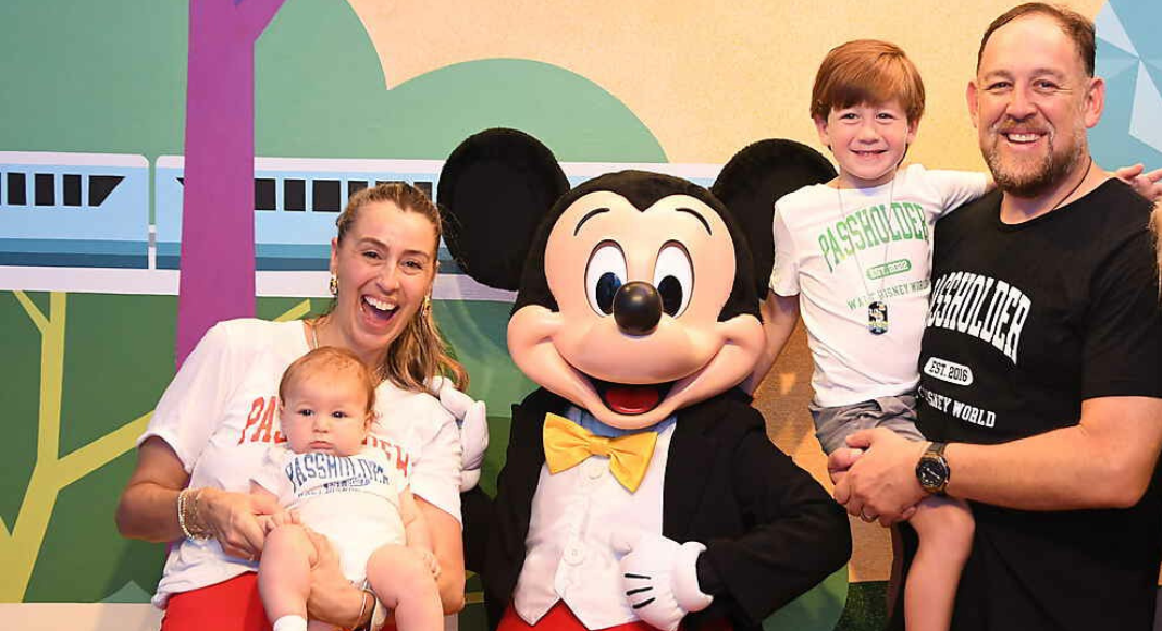 Image: A family of four take a picture with Mickey Mouse