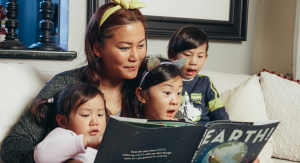 Image: A woman reads a book with her children