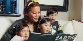 Image: A woman reads a book with her children
