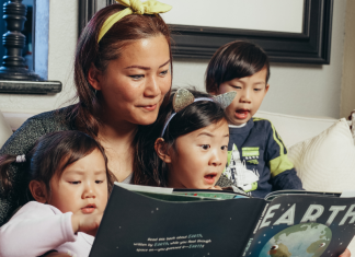 Image: A woman reads a book with her children