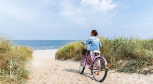 Image: A woman strolls along the beach with her bicycle