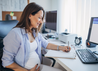 Image: An expectant mother sits at her desk at work