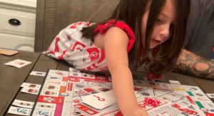 Image: A child plays a board game with her family
