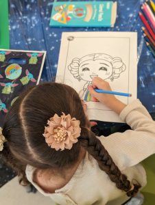 Image: A little girl colors a picture of Princess Leia