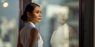 Image: A corporate woman stands at a window in an office building