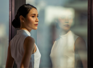 Image: A corporate woman stands at a window in an office building