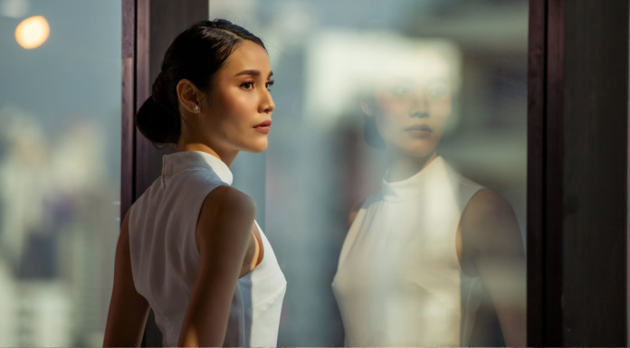 Image: A corporate woman stands at a window in an office building
