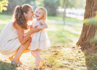 Image: A mom plays with her toddler-aged daughter outdoors during summertime