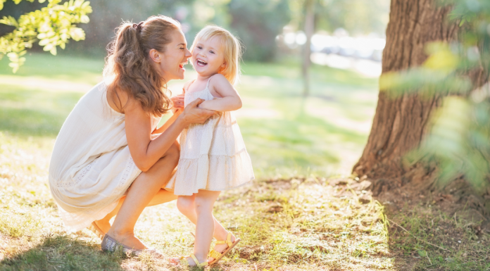 Image: A mom plays with her toddler-aged daughter outdoors during summertime