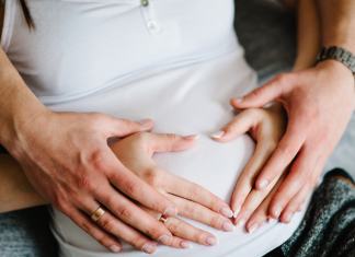 Image: Expectant parents place their hands on the mother's belly in the shape of a heart
