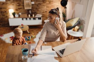 Image: A mom working from home while her toddler plays beside her