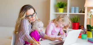 Image: A working mom trying to work from home with a toddler on her lap and a preschooler next to her