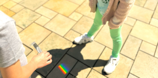 Embracing Neurodiversity: Celebrating Autism Acceptance Month Image: Students use a prism outdoors to cast a rainbow on stone pavers