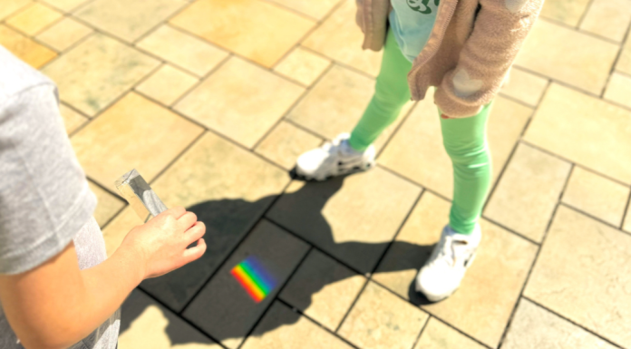 Embracing Neurodiversity: Celebrating Autism Acceptance Month Image: Students use a prism outdoors to cast a rainbow on stone pavers