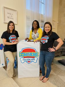 Image: Valerie and two of her mom friends pose next to a donation box at a Paw Patrol birthday party