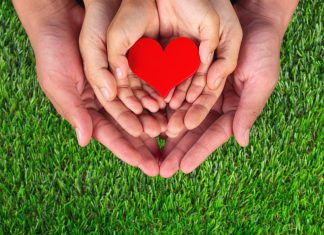 Raising Kind, Generous Children: How & Why It’s Important Image: Three sets of hands holding a red heart