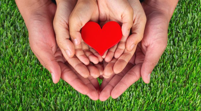 Raising Kind, Generous Children: How & Why It’s Important Image: Three sets of hands holding a red heart